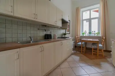 a kitchen with white cabinets and a sink and a table at Ground Floor Family Apartment in Kraków