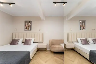a bedroom with two beds and a chair and a mirror at Erasmus Student Apartments - Old Town in Kraków