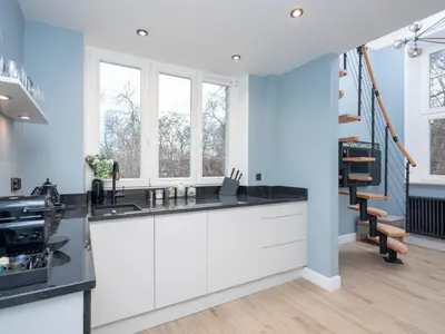 a kitchen with white cabinets and blue walls at Erasmus Student Apartments - Old Town in Kraków
