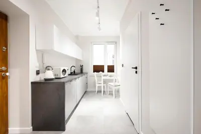 a kitchen with white cabinets and a black counter top at Rakowicka 71 Partnerapart in Kraków