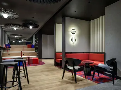a living room with a red couch and chairs at Hotel Ibis Krakow Centrum in Kraków