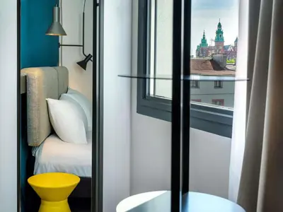 a bedroom with a bed and a blue wall at Hotel Ibis Krakow Centrum in Kraków