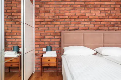 a bedroom with a brick wall and a bed and a mirror at Olimp Apartments in Kraków
