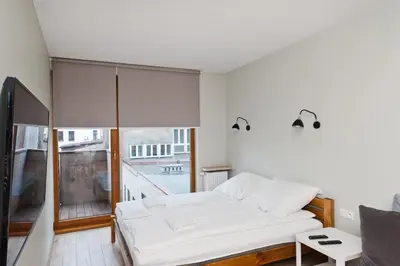 a bedroom with a bed and a large window at Olimp Apartments in Kraków