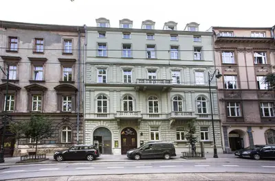 a large white building with cars parked in front of it at Aparthotel Old Town in Kraków