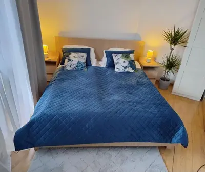 a bedroom with a blue bed with blue sheets and pillows at GreenApartament in Kraków
