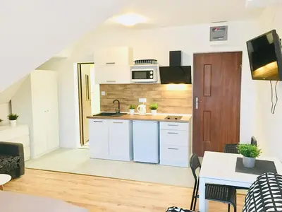 a kitchen with white cabinets and a sink and a table at Willa Kamilówka in Rabka