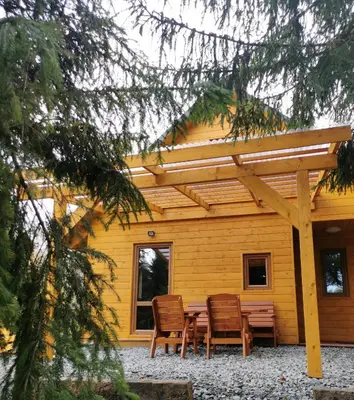a table and chairs in front of a yellow house at Zawoja Chaty Górskie D1 in Zawoja