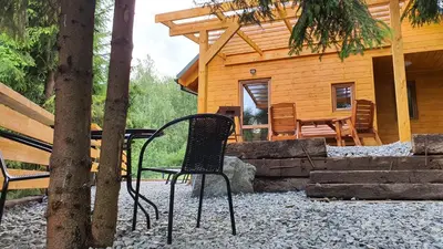 a black chair sitting in front of a cabin at Zawoja Chaty Górskie D1 in Zawoja