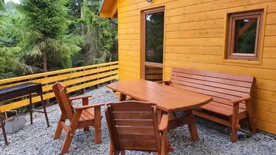 a wooden table and chairs and a wooden bench on a cabin at Zawoja Chaty Górskie D1 in Zawoja