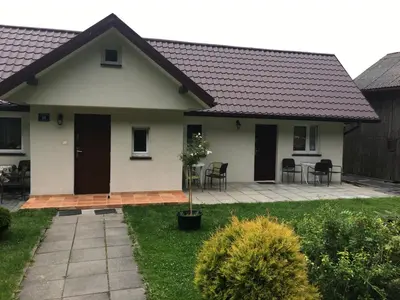 a white house with a patio and table and chairs at Nasza Polana Pokoje Noclegi Pieskowa Skała Ojców in Pieskowa Skała