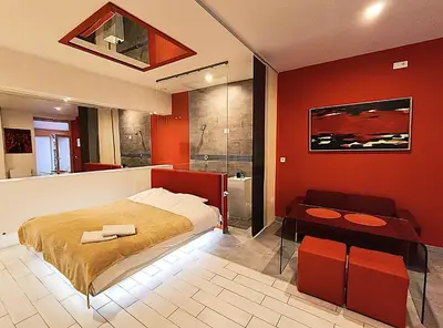a bedroom with red walls and a bed and a bathroom at Mirror Apartments in Kraków
