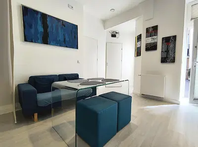 a living room with a glass table and blue chairs at Mirror Apartments in Kraków