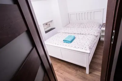 a small white bed with a blue towel on it at Mirror Apartments in Kraków