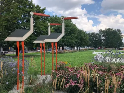 a sculpture of two benches in a park with flowers at Studio z ogrodem przy Starej Zajezdni in Kraków