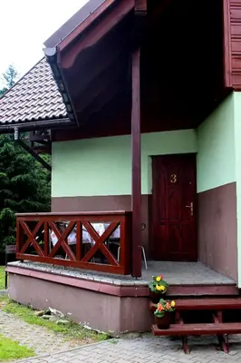 a house with a red door and a bench and flowers at Zawoja Chaty Górskie D3 in Zawoja