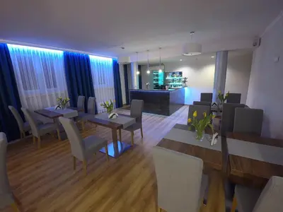a dining room with tables and chairs and a kitchen at Brojan in Jaworzno