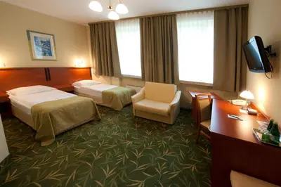 a hotel room with two beds and a chair at Brojan in Jaworzno