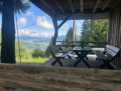 a picnic table and two benches on the porch of a cabin at Gościniec pod Lubomirem in Węglówka