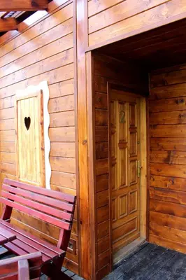 a wooden cabin with a bench and a door at Zawoja Chaty Górskie D2 in Zawoja