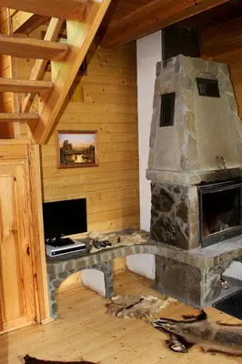 a living room with a stone fireplace in a cabin at Zawoja Chaty Górskie D2 in Zawoja
