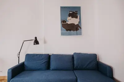 a blue couch in a living room with a poster of a cow at Michałowskiego 11 in Kraków