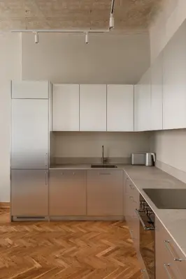 a kitchen with white cabinets and a wooden floor at Michałowskiego 11 in Kraków