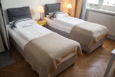 two beds in a small room with two lamps at Rondo Mogilskie Apartment in Kraków