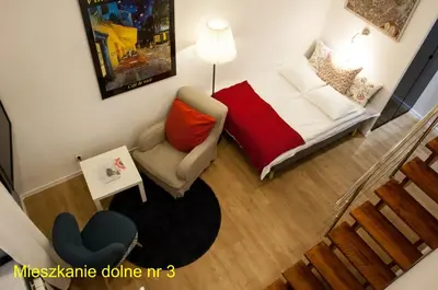a small living room with a bed and a chair at Rondo Mogilskie Apartment in Kraków