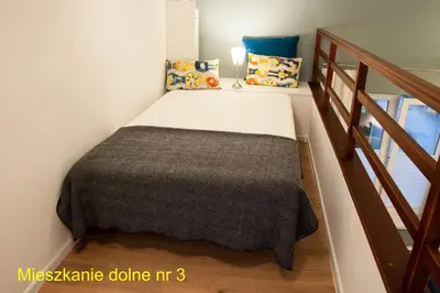 a small bed in a room with a staircase at Rondo Mogilskie Apartment in Kraków