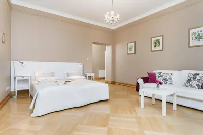 a white bedroom with a bed and a couch at Apartamenty w Pałacu Pod Baranami in Kraków