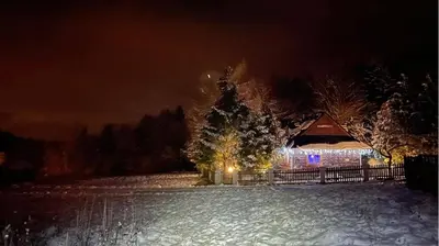 a house with lights in a snowy yard at night at Góralska Czarcia Chata pod Jałowcem in Stryszawa