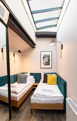 two beds in a room with a skylight at Stradom15 Apartments in Kraków