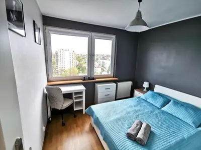 a bedroom with a bed and a desk and a window at Sky Apartments - Łagiewniki in Kraków
