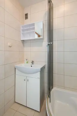 a white bathroom with a sink and a shower at Studio Aleja Pokoju II in Kraków