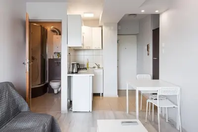 a living room with a table and a kitchen at Studio Aleja Pokoju II in Kraków