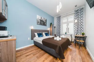 a bedroom with a bed with blue walls and a table at Grace Apartments in Kraków