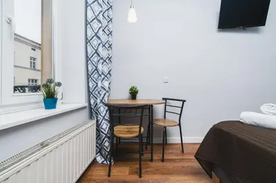 a small table and two chairs in a room with a window at Grace Apartments in Kraków
