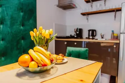 a bowl of fruit on a table with a vase of flowers at Kings City - Zyblikiewicza Apartment in Kraków