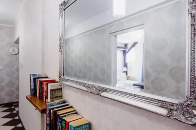 a mirror on a wall with books on a shelf at Kings City - Zyblikiewicza Apartment in Kraków