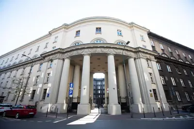 a large white building with columns in a parking lot at Kings City - Zyblikiewicza Apartment in Kraków