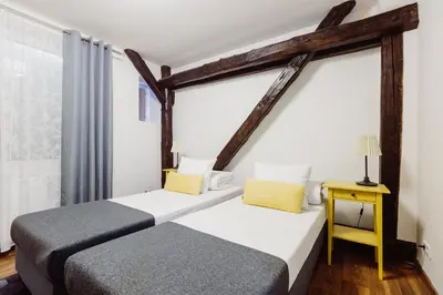 a bedroom with two beds and a table with a lamp at Kings City - Zyblikiewicza Apartment in Kraków