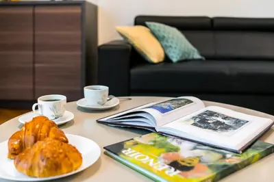 a table with a book and a plate of bread and coffee cups at Old Town Residence Bis in Kraków