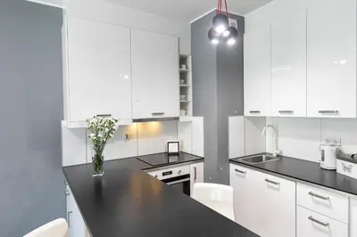 a kitchen with white cabinets and a black counter top at Apartamenty Lucky 13 in Kraków