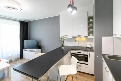 a kitchen with white cabinets and a black counter top at Apartamenty Lucky 13 in Kraków