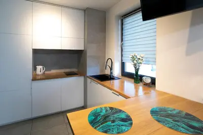 a kitchen with white cabinets and a wooden table at Apartamenty Lucky 13 in Kraków