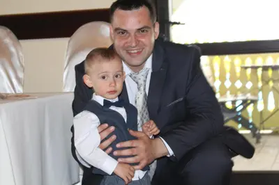 a man holding a young boy in a suit and bow tie at Zajazd Turystyczny Stara Gawęda in Czechówka