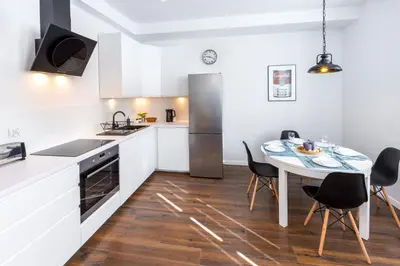 a kitchen with a table and a kitchen with white cabinets at Arianska Residence in Kraków