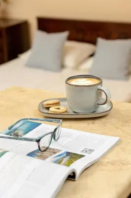 a cup of coffee on a table with a book and glasses at Caffe latte apartment in Kraków