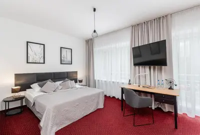 a bedroom with a bed and a desk and a television at Hotel Łaziska in Czchów